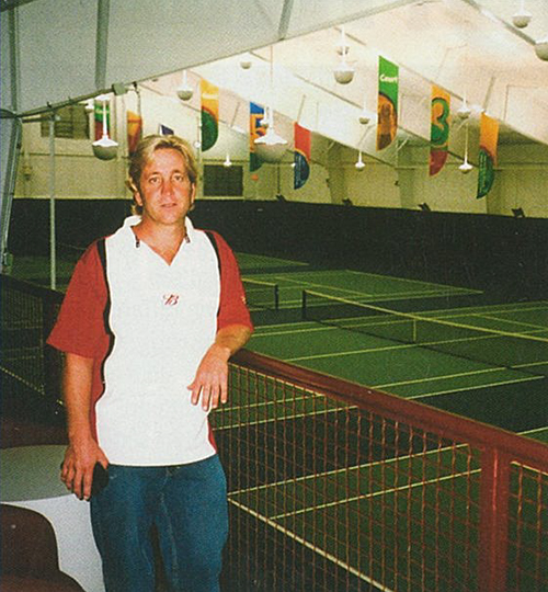 A photo Rob Werner in 2007 posing in front on indoor tennis courts.